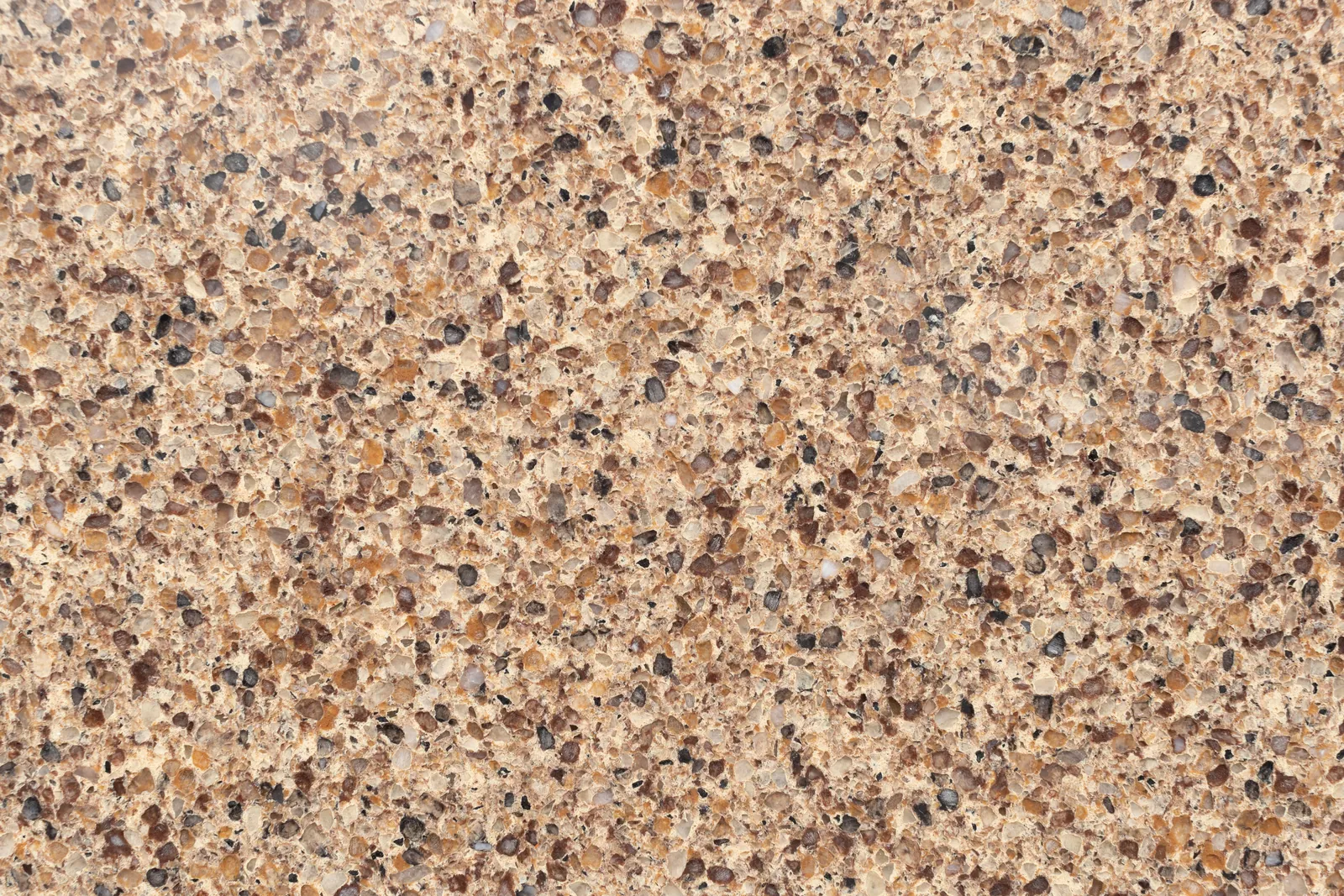 Cận cảnh bề mặt đá Vicostone Nirvara™ BQ9140, vàng cát ấm với hạt lớn nâu, đen và kem, hiệu ứng đá hoa cương rõ nét
